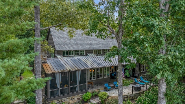 rear view of house featuring a fire pit, a sunroom, and a patio area