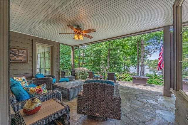 sunroom / solarium with ceiling fan and a water view