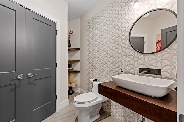 bathroom with toilet, built in features, and sink