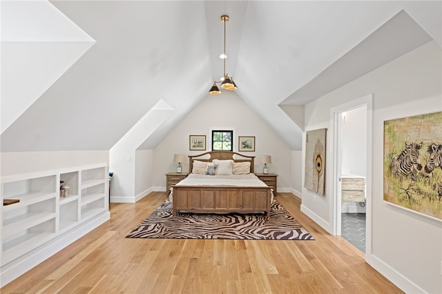 bedroom featuring light hardwood / wood-style floors, lofted ceiling with skylight, and ensuite bathroom