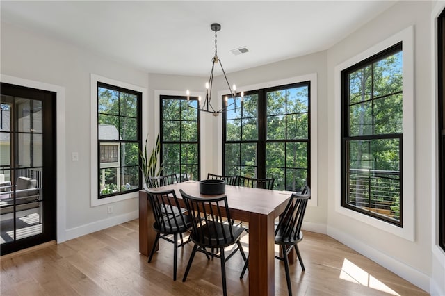 dining area featuring light wood-type flooring, a wealth of natural light, and a notable chandelier