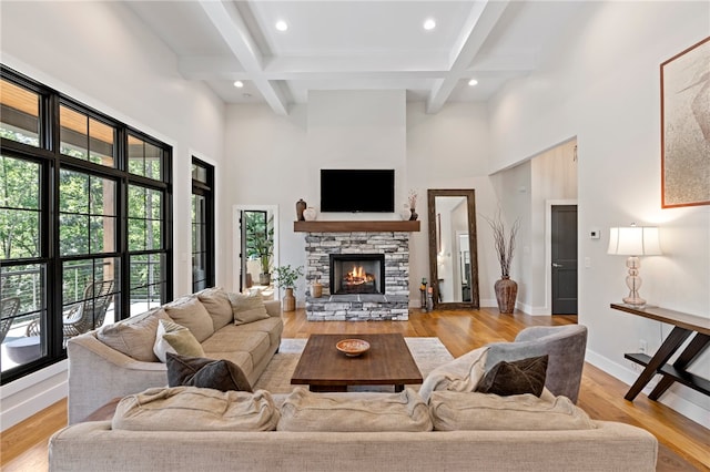 living room with beamed ceiling, light hardwood / wood-style floors, and a high ceiling