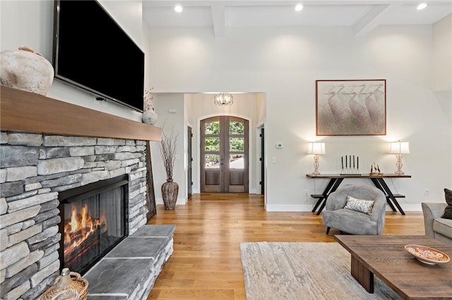 living room with beam ceiling, light wood-type flooring, and a stone fireplace