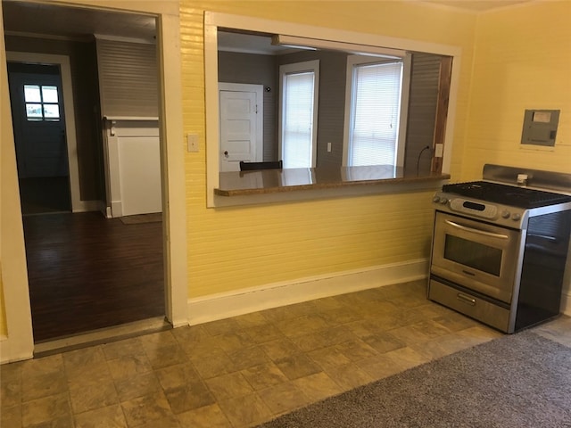 kitchen with crown molding, wooden walls, dark hardwood / wood-style floors, and stainless steel stove