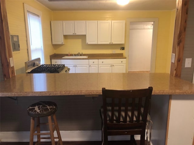 kitchen with white cabinets, a breakfast bar area, and sink