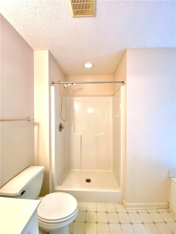 bathroom featuring a shower, vanity, a textured ceiling, and toilet