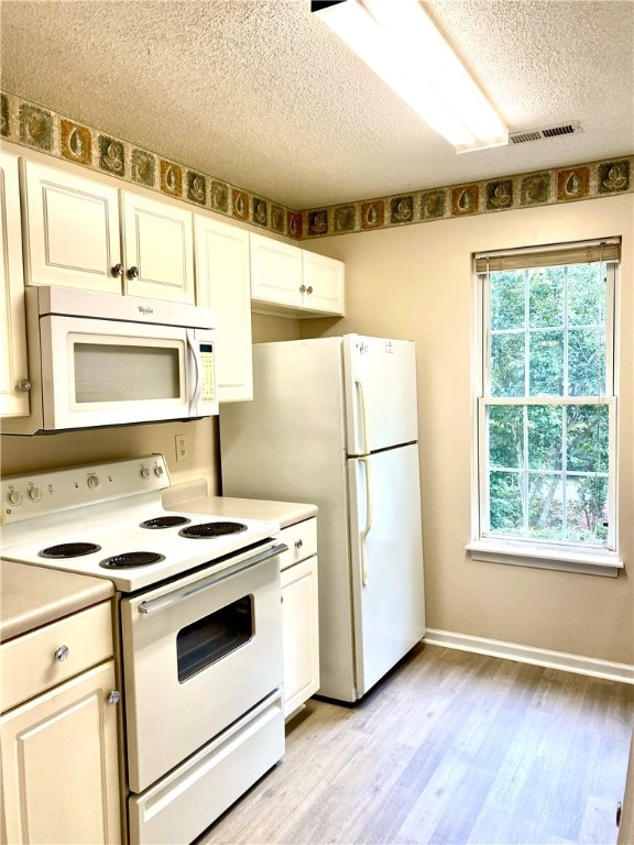 kitchen featuring a textured ceiling, light hardwood / wood-style flooring, white cabinets, and white appliances