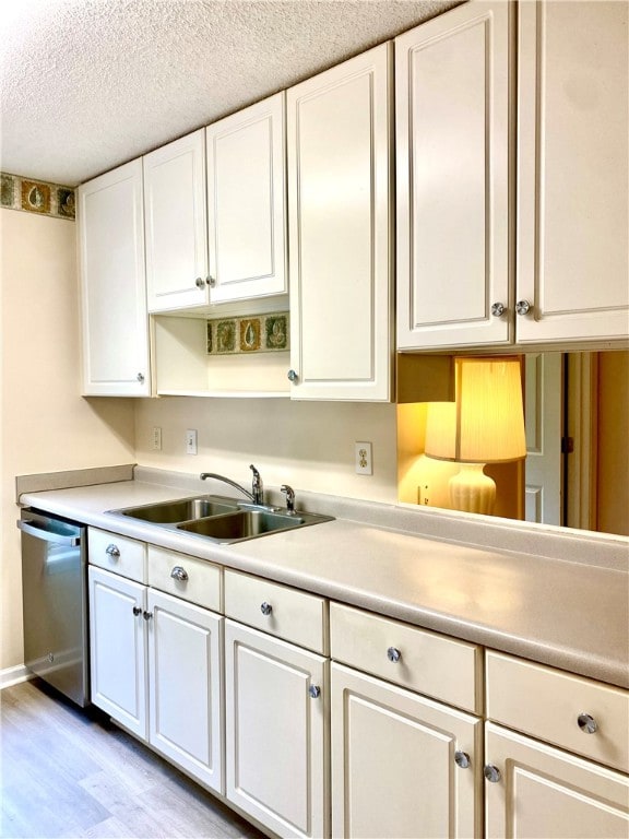 kitchen with light wood-type flooring, stainless steel dishwasher, a textured ceiling, sink, and white cabinetry