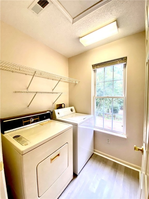 laundry room with hardwood / wood-style flooring, washing machine and dryer, and a textured ceiling