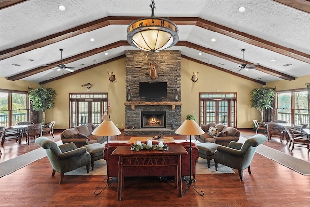 living room featuring a stone fireplace, ceiling fan, a wealth of natural light, and a textured ceiling