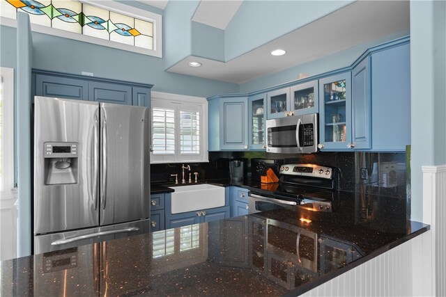 kitchen featuring dark stone countertops, stainless steel appliances, sink, and blue cabinetry