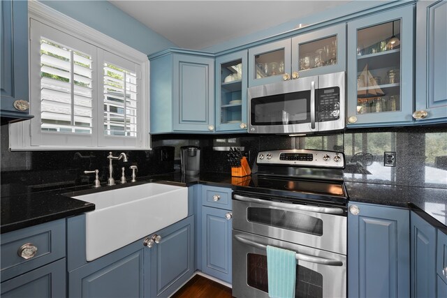 kitchen with appliances with stainless steel finishes, sink, tasteful backsplash, and blue cabinetry