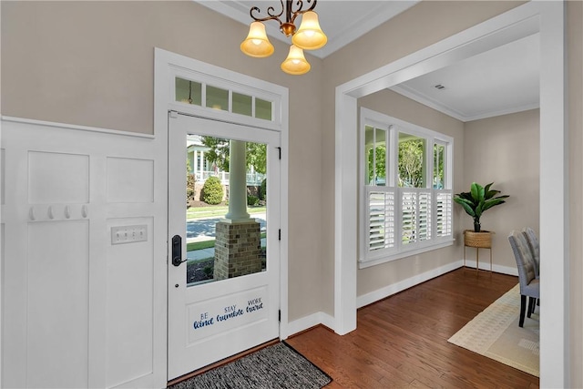 entrance foyer with ornamental molding, an inviting chandelier, dark hardwood / wood-style floors, and a wealth of natural light