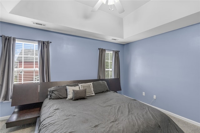 unfurnished bedroom with a tray ceiling, ceiling fan, multiple windows, and carpet floors