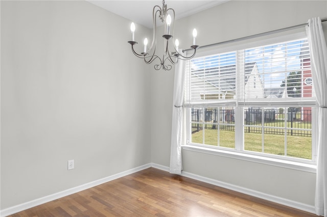 unfurnished dining area with wood-type flooring and a notable chandelier