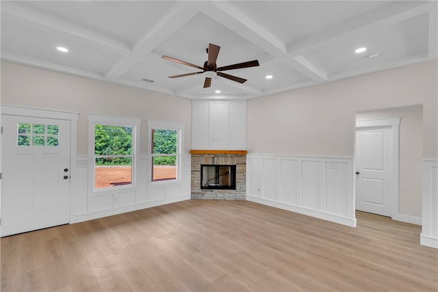 unfurnished living room with ceiling fan, beamed ceiling, coffered ceiling, a fireplace, and light wood-type flooring