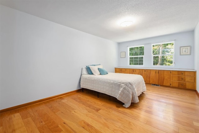 bedroom with a textured ceiling and light hardwood / wood-style floors