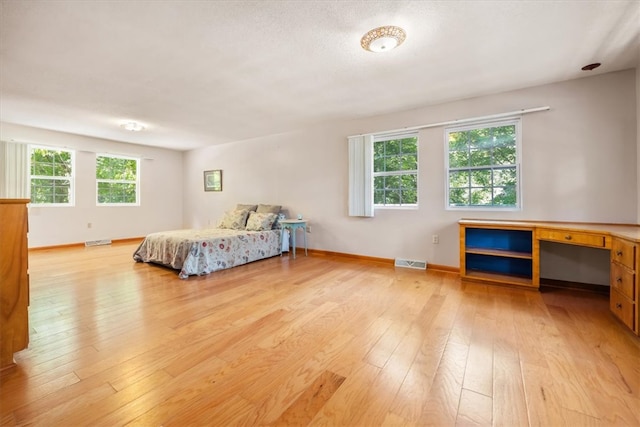 bedroom with light hardwood / wood-style flooring, built in desk, and multiple windows