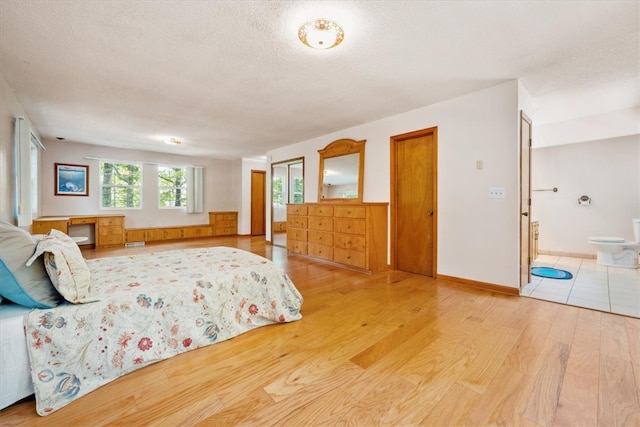 unfurnished bedroom with wood-type flooring, built in desk, connected bathroom, and a textured ceiling