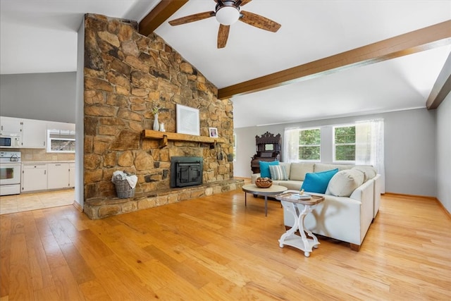 living room featuring ceiling fan, lofted ceiling with beams, light hardwood / wood-style floors, and a wood stove