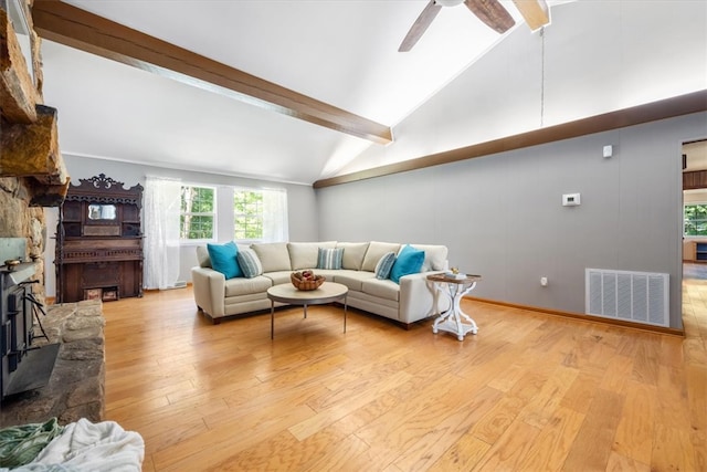 living room with a stone fireplace, vaulted ceiling with beams, light wood-type flooring, and ceiling fan