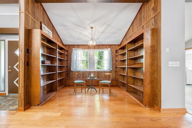 interior space featuring built in shelves, light hardwood / wood-style floors, wood walls, and vaulted ceiling