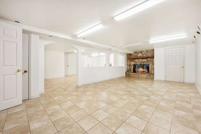 unfurnished living room with light tile patterned flooring and a stone fireplace