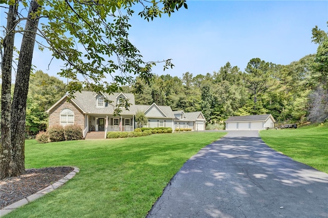 new england style home with a front lawn, covered porch, an outbuilding, and a garage