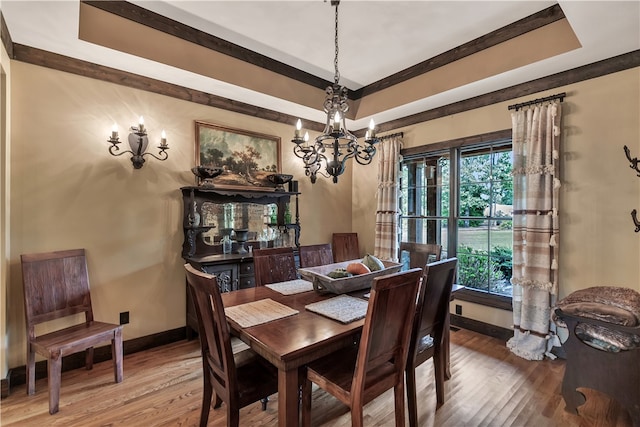 dining space with an inviting chandelier, a raised ceiling, and hardwood / wood-style floors