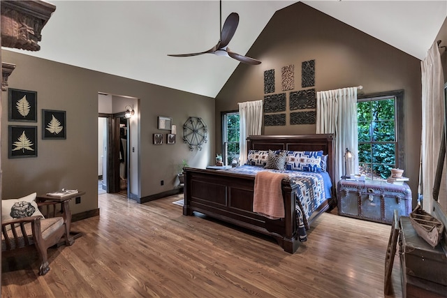 bedroom with high vaulted ceiling, ceiling fan, multiple windows, and hardwood / wood-style floors