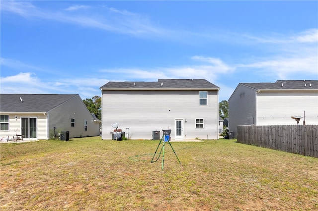 rear view of house with cooling unit and a lawn