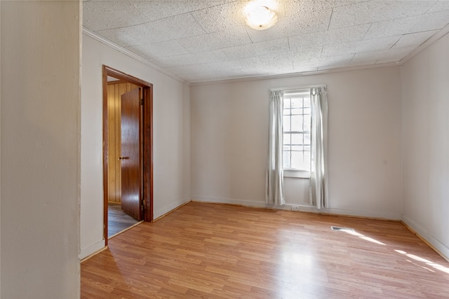 spare room featuring light hardwood / wood-style flooring and crown molding