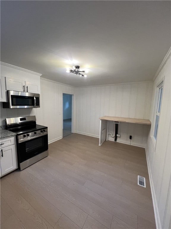 kitchen with light stone counters, stainless steel appliances, light wood-type flooring, and white cabinetry