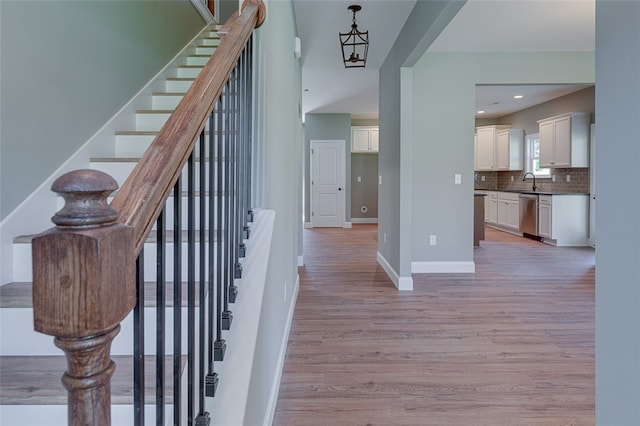 stairway with an inviting chandelier, wood-type flooring, and sink