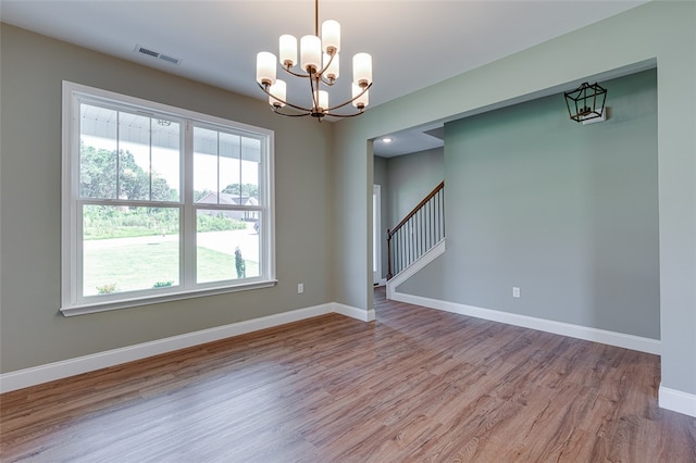 unfurnished room featuring wood-type flooring and a chandelier