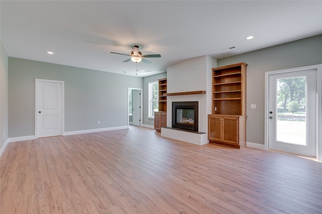 unfurnished living room featuring light wood-type flooring, ceiling fan, and a large fireplace