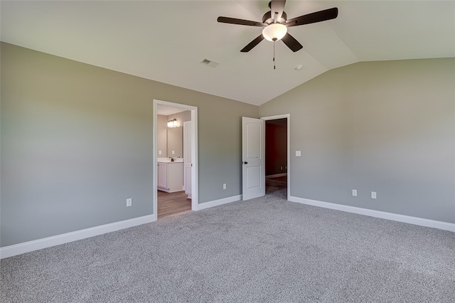 unfurnished bedroom featuring ceiling fan, carpet floors, lofted ceiling, and ensuite bath