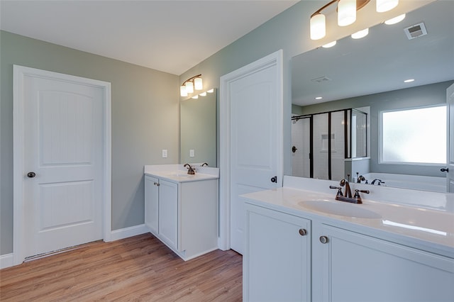 bathroom with plus walk in shower, hardwood / wood-style flooring, and vanity