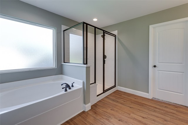 bathroom featuring wood-type flooring and separate shower and tub