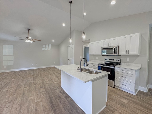 kitchen featuring hanging light fixtures, sink, white cabinetry, hardwood / wood-style flooring, and stainless steel appliances