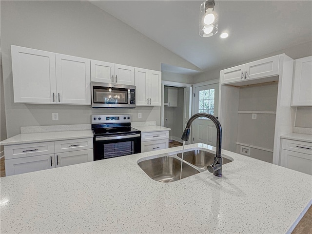 kitchen with sink, white cabinetry, appliances with stainless steel finishes, light stone countertops, and vaulted ceiling