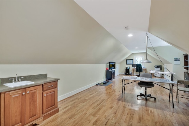 office area with lofted ceiling, sink, and light hardwood / wood-style flooring