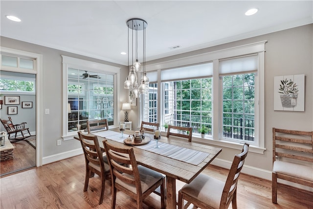 dining space with a wealth of natural light, light hardwood / wood-style floors, and crown molding