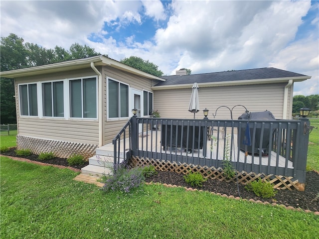 back of property featuring a wooden deck and a yard