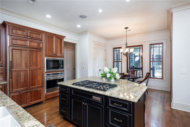 kitchen with light stone counters, a chandelier, dark wood-type flooring, built in appliances, and ornamental molding