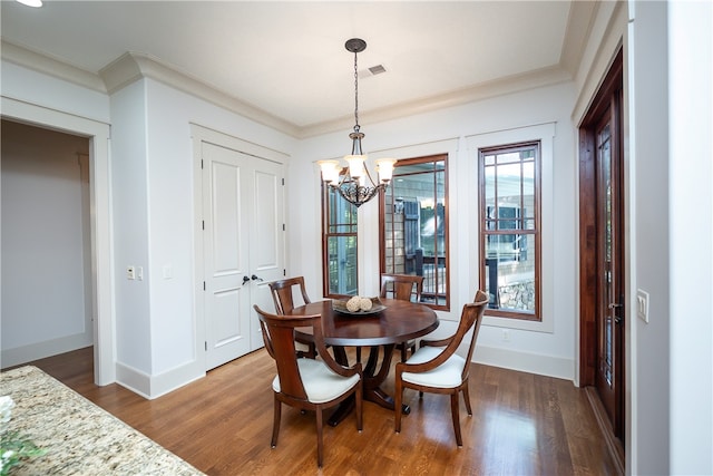 dining space with ornamental molding, hardwood / wood-style floors, and a chandelier