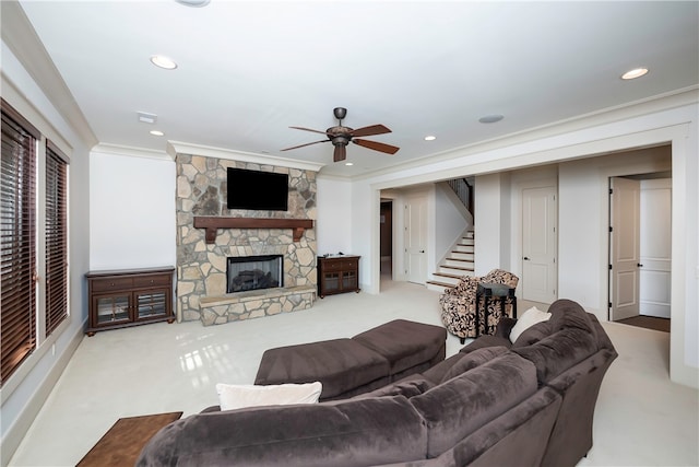 living room featuring crown molding, a stone fireplace, ceiling fan, and light colored carpet