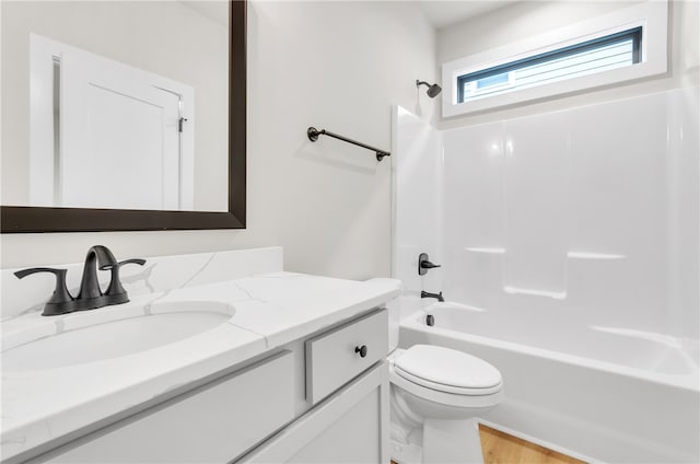 full bathroom with hardwood / wood-style flooring, bathing tub / shower combination, vanity, and toilet