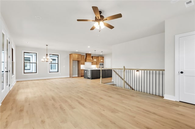 unfurnished living room featuring ceiling fan with notable chandelier and light wood-type flooring