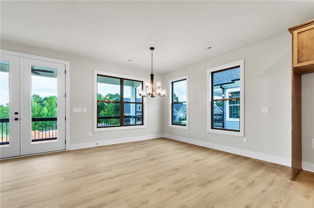 unfurnished dining area with french doors, a wealth of natural light, a chandelier, and light wood-type flooring